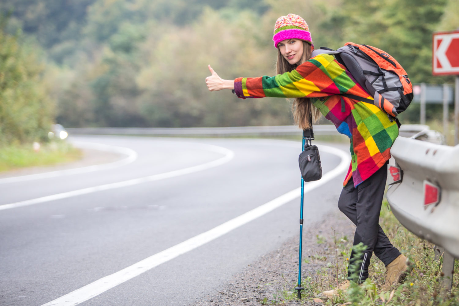 Young woman hitchhiking on a road from Lisbon to Faro