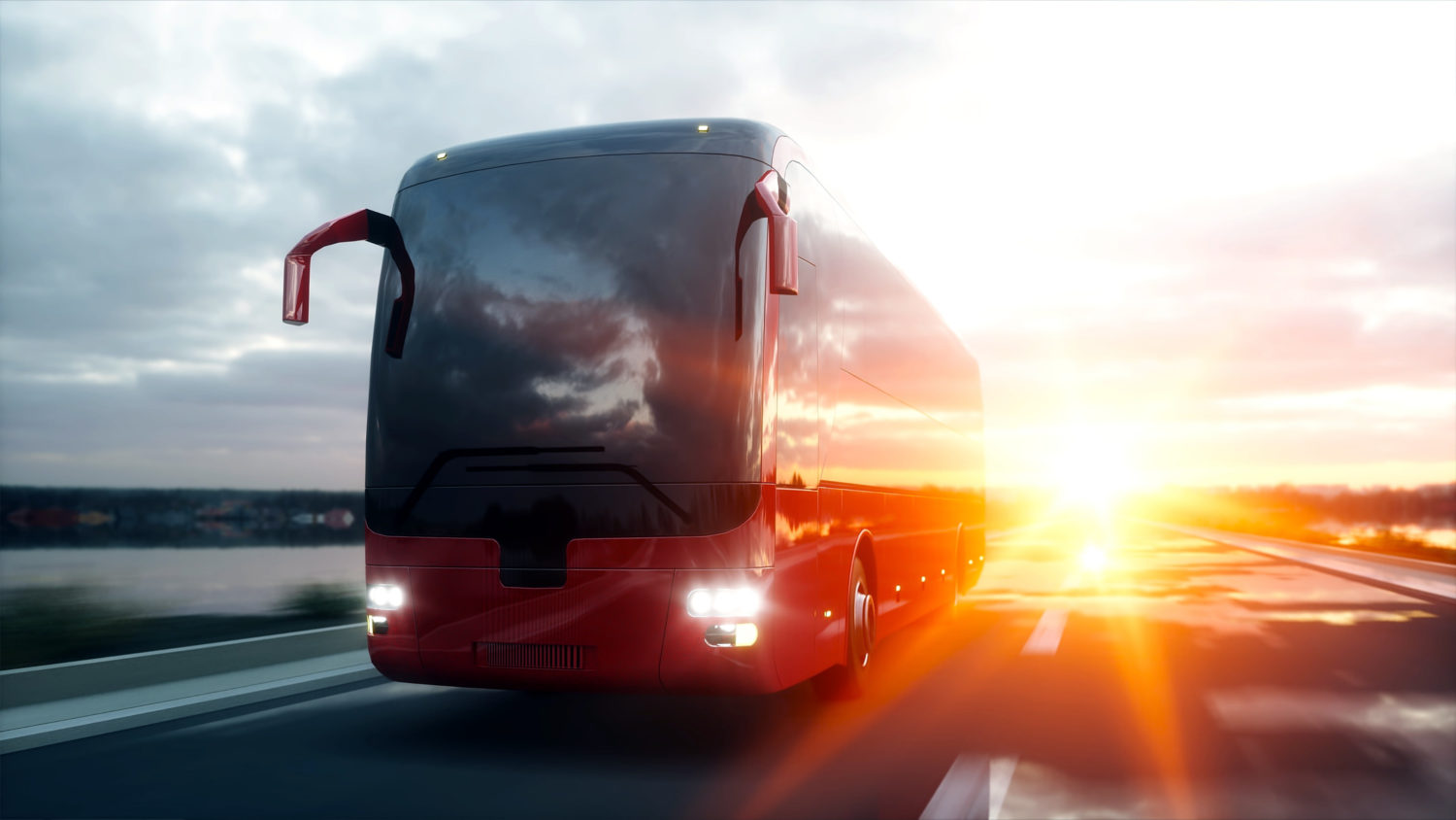 Red bus driving on a road with sunset behind it 