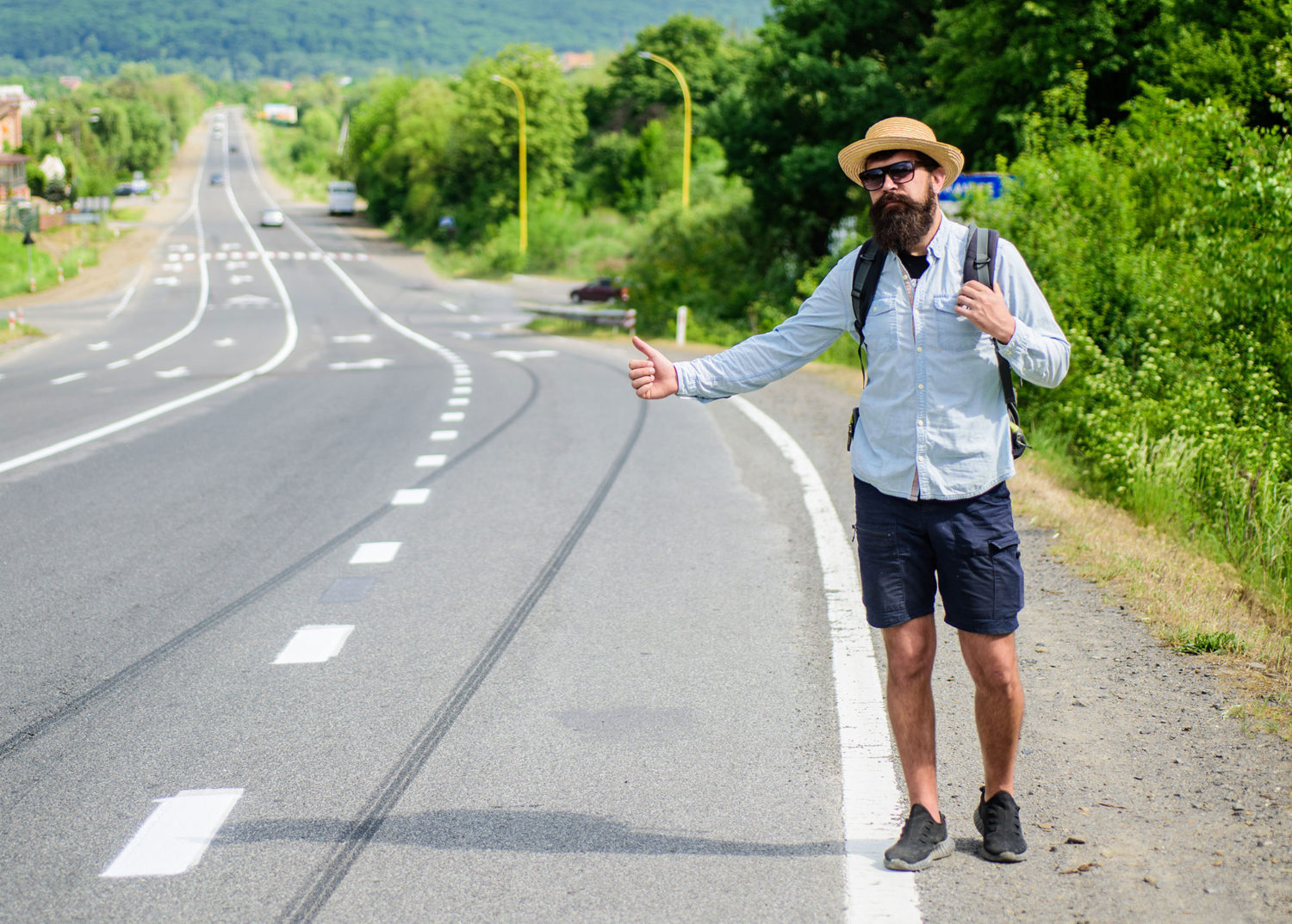 Bearded hipster man hitch-hiking on a road from Prague to Leipzig