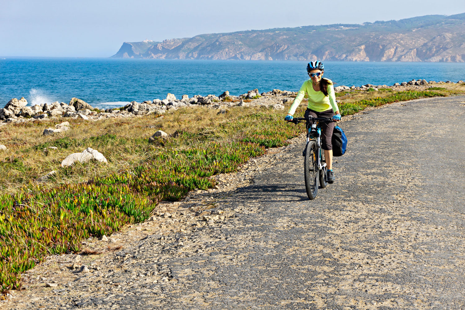 Woman cycling on a seaside road in Portugal